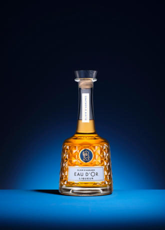 Bouteille de liqueur Eau d'Or, design élégant avec étiquette blanche et logo bleu, présentée sur fond bleu profond.